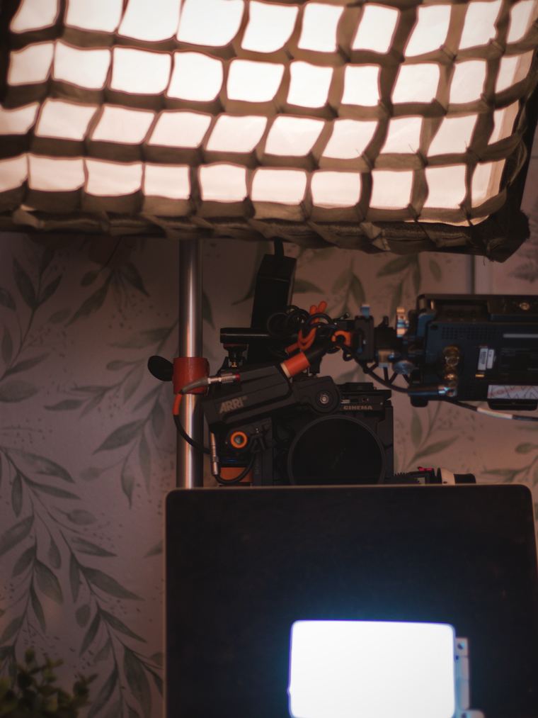 A softbox rigged directly above the camera on the bedroom set