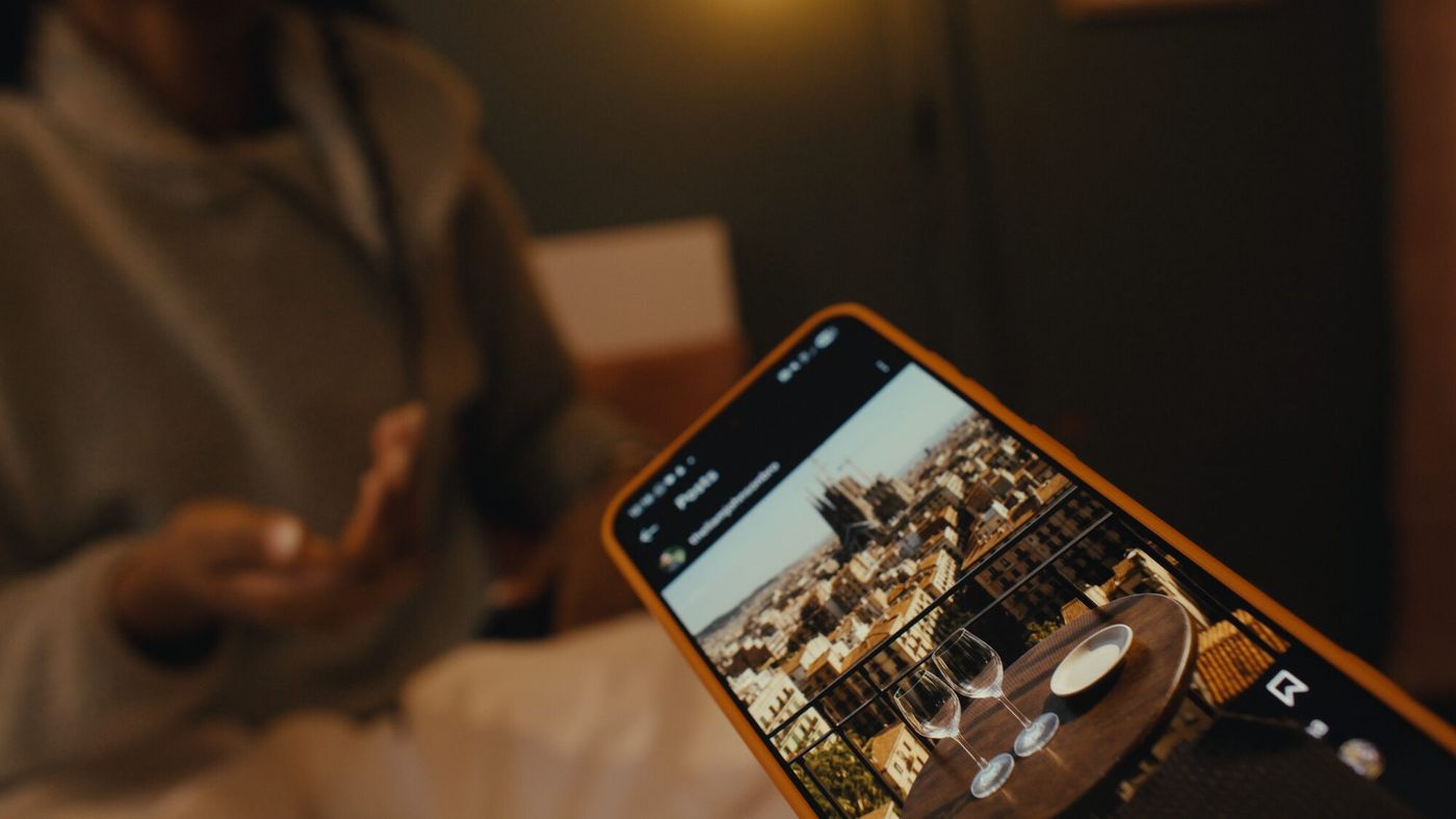 A hand holds a phone showing a photograph, thumb hovering over the screen